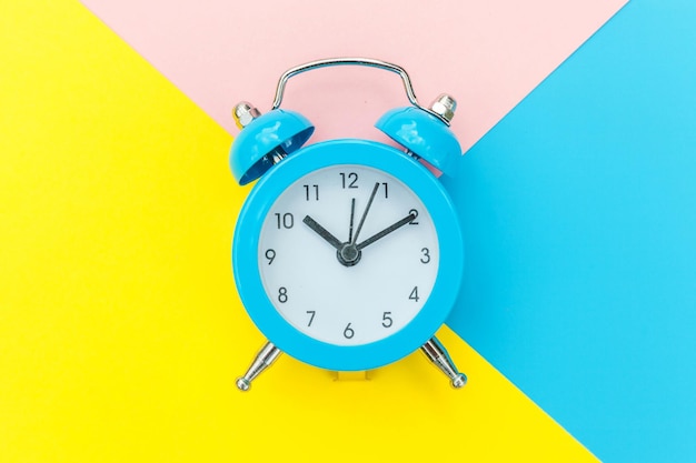 Suena el reloj despertador clásico twin bell aislado sobre fondo geométrico colorido pastel rosa amarillo azul. Horas de descanso tiempo de vida buenos días noche despierta concepto despierto. Espacio de copia de vista superior endecha plana.