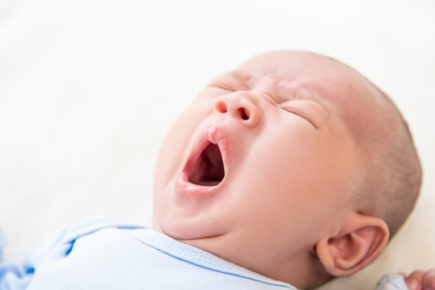 Sueño adorable bebé recién nacido bostezando en la cama