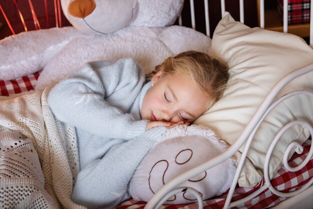 Sueño sereno en la cama de una niña y un oso de juguete.