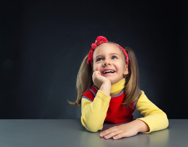 Sueños de niña linda sonriendo con la mano debajo de la barbilla