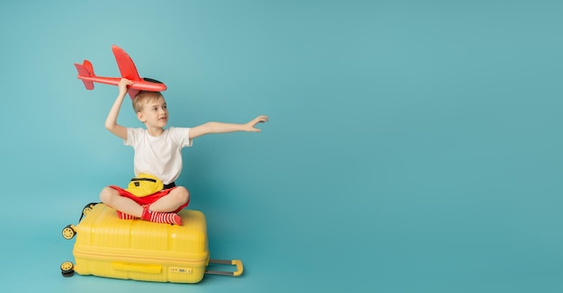 Sueños de viaje Niño volando en una maleta sobre el fondo azul.