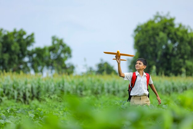 ¡Sueños de vuelo! Niño indio jugando con avión de juguete en campo verde