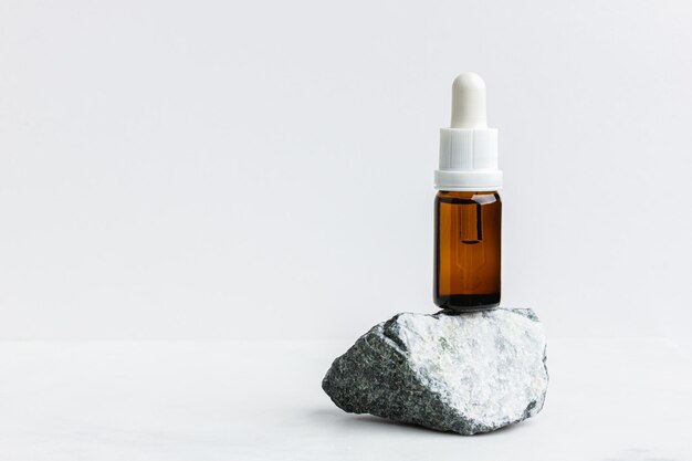 Suero en la botella marrón para la cara sobre mármol blanco Herramienta cosmética de moda Terapia antienvejecimiento Vista lateral Lay plano Espacio de copia