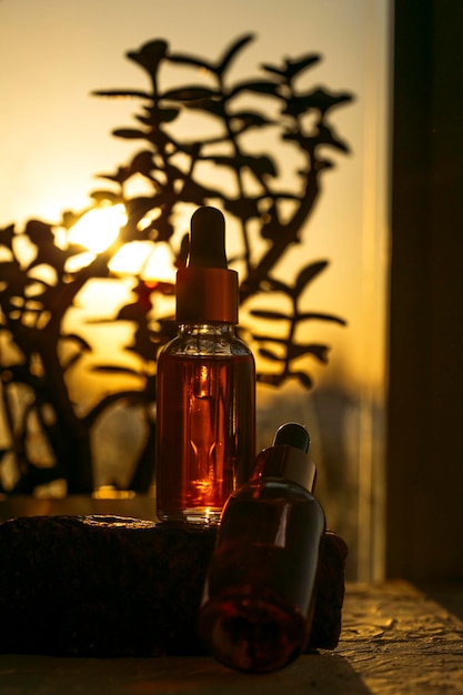 Foto suero en una botella de vidrio sobre un fondo natural de aceite esencial para el cuidado de la piel