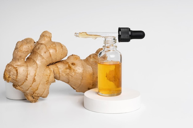 Un suero o aceite amarillo jengibre en una botella de gotero para la cara o el cuerpo de pie en un podio de hormigón blanco