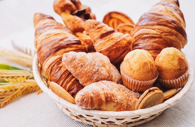 Süße Bäckereiprodukte und Croissants im Korb, von oben aus gesehen mit weißem Hintergrund