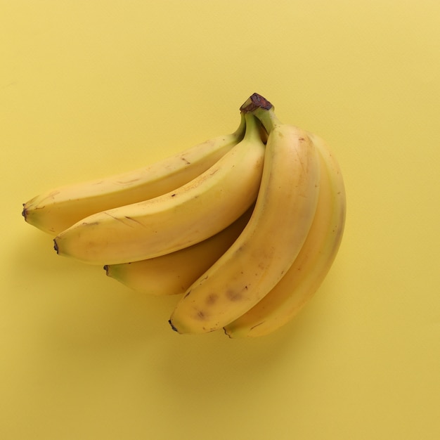 Süße Bananen auf druckvollem pastellgelbem Hintergrund, Draufsicht, Nahaufnahme