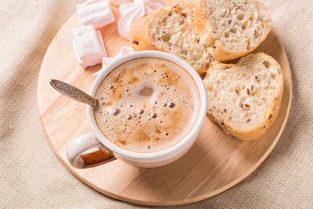 Süße Brötchen, Meringues und Kaffeetasse auf einem Holzbrett