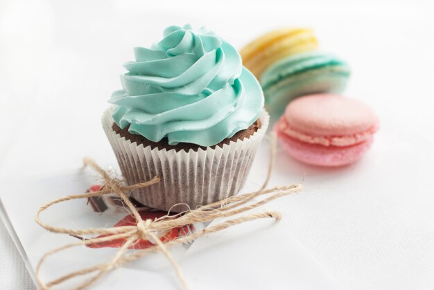 Süße bunte Makrone mit kleinem Kuchen auf weißem Tisch. Desserts als Geschenk für gute Laune