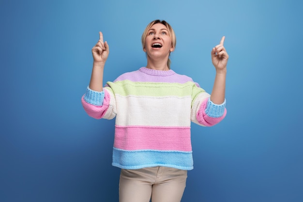 Süße charmante blonde junge Frau in einem gestreiften Pullover zeigt freudige Glücksgefühle auf a