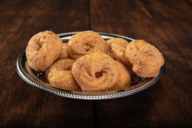 Süße Donuts in Edelstahlschale auf rustikalem Holz, selektiver Fokus.