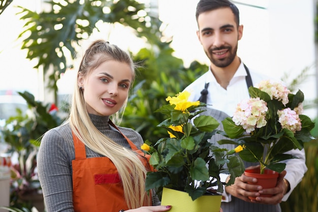 Süße Floristen halten Blumen in Töpfen professionelle Berater bereit, bei der Auswahl zu helfen