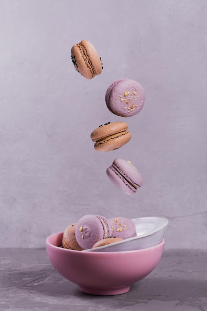 Süße französische Macarons fallen auf grauem Hintergrund in Bewegung