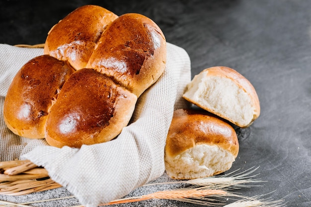 Süße frische Brötchen im Korb auf schwarzem Holzhintergrund