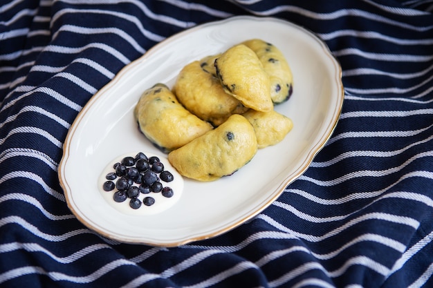 Süße Fruchtknödel mit frischen Waldheidelbeeren. Hausgemachte frische Knödel auf einem schönen Teller mit Sauerrahm.