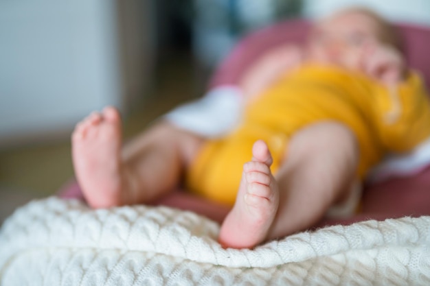 Süße Füße eines Babys in einem gelben Body