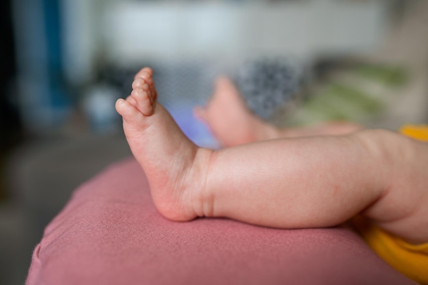 Süße Füße eines Babys in einem gelben Body