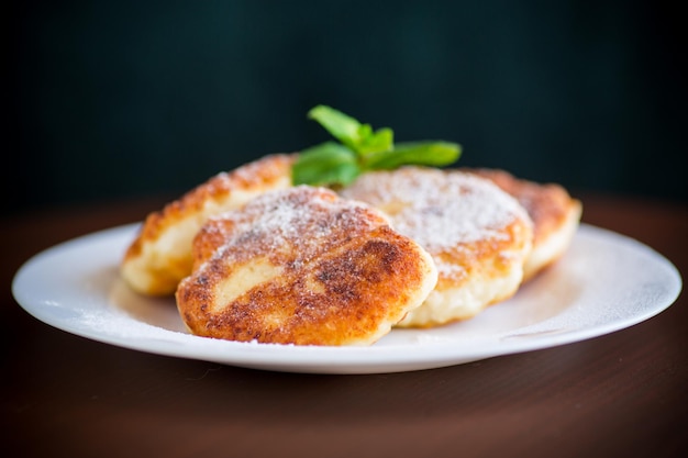 Süße gekochte Käsekuchen in Puderzucker auf einem Teller auf dem Tisch