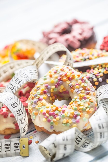 Süße glasierte Donuts und Maßband auf dem Tisch.