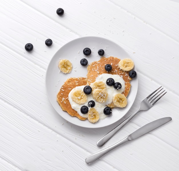 Süße Haferflockenpfannkuchen mit Sahne, Heidelbeere und Banane. Gesundes Frühstückskonzept.