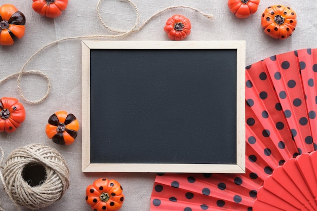 Süße Herbstdekor-Tafel mit Copyspace Orangefarbene Mini-Kürbisse schwarz lackiert und Lüfter mit Tupfen auf beigem Leinen-Textilhintergrund mit Hanfschnur