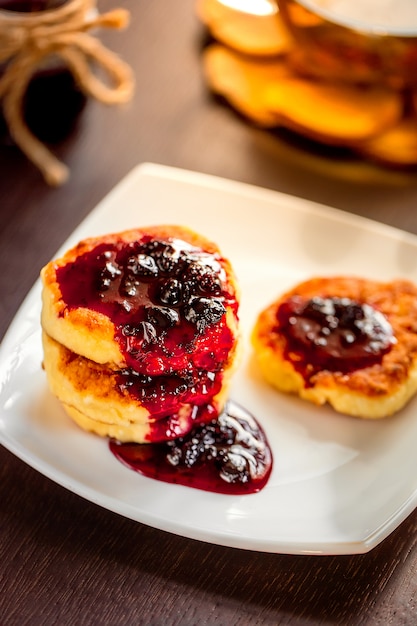 Süße Käsepfannkuchen auf einer weißen Platte mit grünem, Kamillentee