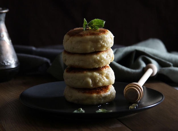 Süße Käsepfannkuchen mit Honig und Sahne auf einem schwarzen Teller Hausgemachte Rezept-Käsekuchen