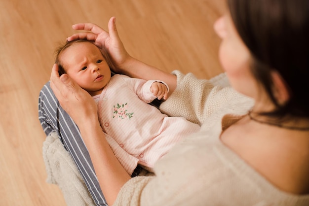 Süße kleine Babymädchen tragen Pyjamas wachen auf, liegend auf Mutterhänden im Bett zu Hause im Zimmer Nahaufnahme Draufsicht Frau mit kleinem Kleinkind Gesunder Lebensstil Mutterschaft