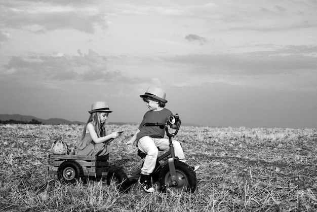 Süße kleine Bauern Schwester und Bruder auf Dreirad auf Feldwirtschaft und Landwirtschaft zwei