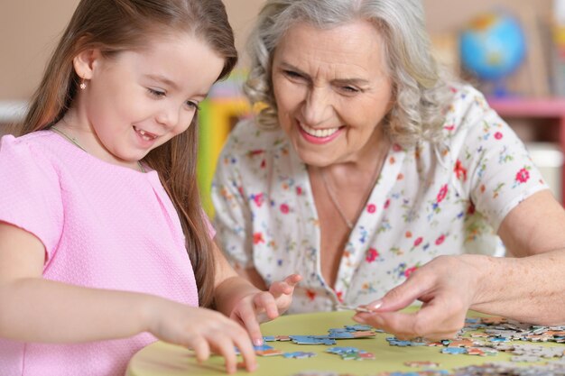 Süße kleine Enkelin und Großmutter sammeln Puzzles