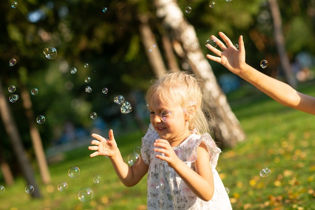 Süße kleine Kinder Jungen und Mädchen bläst Seifenblasen im Herbstpark an einem sonnigen Tag.