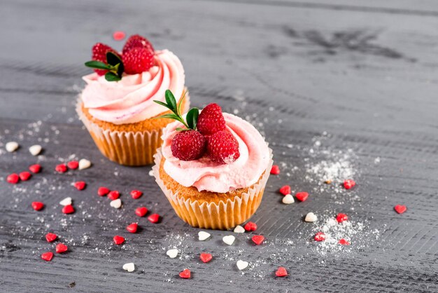 Süße kleine Kuchen mit Himbeeren auf dem hölzernen Hintergrund