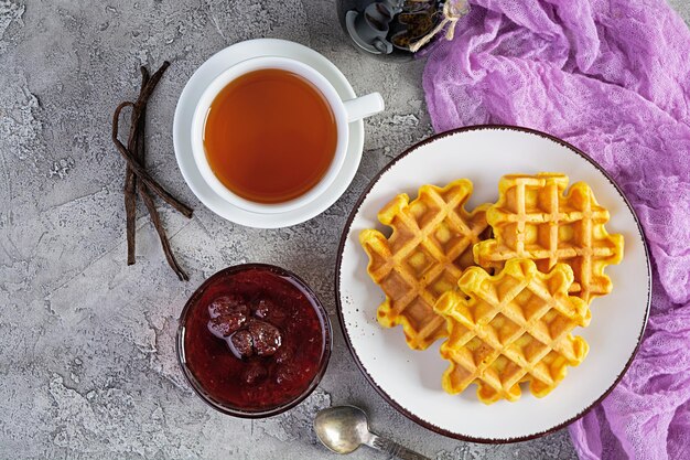 Süße Kürbiswaffeln mit Erdbeermarmelade. Leckeres Frühstück mit belgischen Waffeln. Ansicht von oben