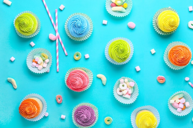 Süße leckere Cupcakes mit Bonbons auf farbigem Hintergrund