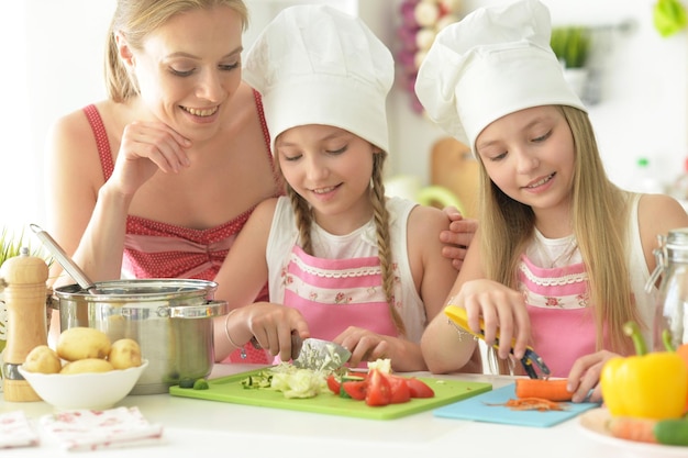 Süße Mädchen mit Mutter bereiten köstlichen frischen Salat in der Küche zu