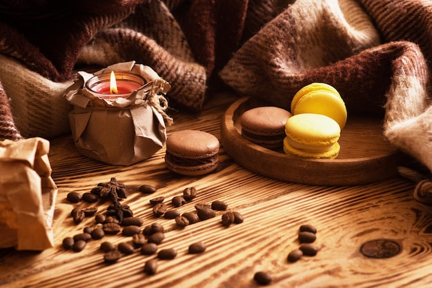 Süße Makronen auf Holzbrett mit einer Tasse Kaffee und einer brennenden Kerze Atmosphärischer Fotoinhalt für soziale Netzwerke