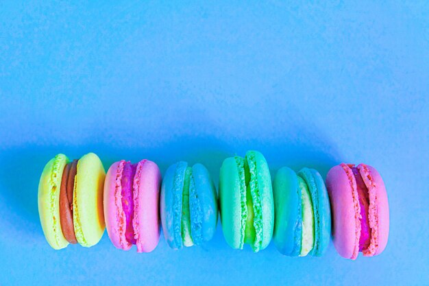 Süße Mandel bunt rosa blau gelb grün Macaron oder Makronen Dessertkuchen isoliert auf trendigem Blau ...