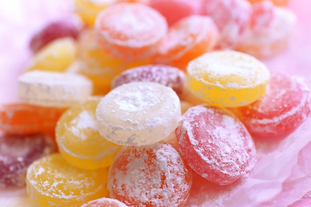 Süße mehrfarbige Bonbons auf Papier auf farbigem Hintergrund