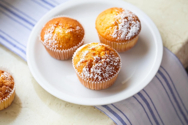 Süße Muffins mit Puderzucker und Blüten Hausgemachte Backmuffins in weißen Kapseln, dekoriert mit Obstbaumblüten