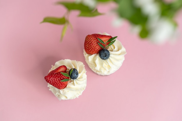 Süße Pfannkuchen mit Beeren auf einer rosa Oberfläche