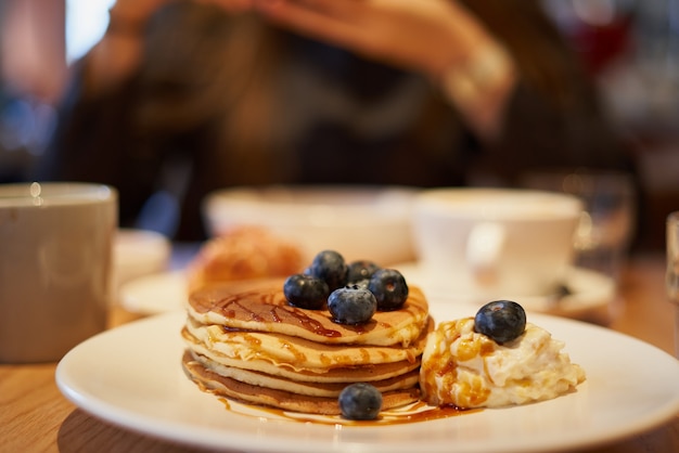 Süße Pfannkuchen mit Karamellsirup Blaubeeren und Eis auf Teller im Café