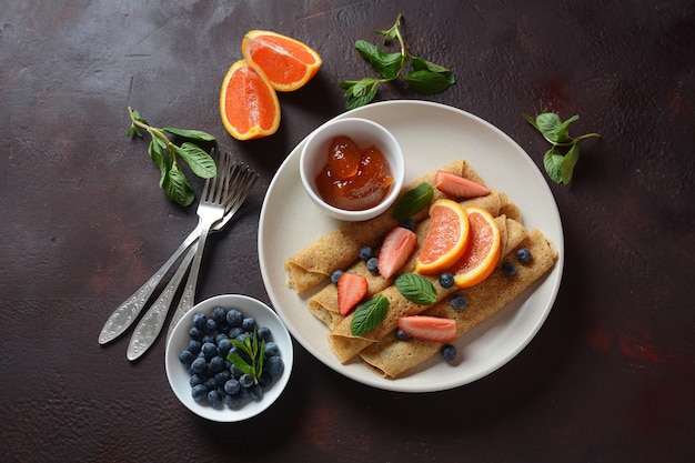 Süße Pfannkuchen umwickelt mit frischer Minze Erdbeeren Blaubeeren Orangen und Marmelade