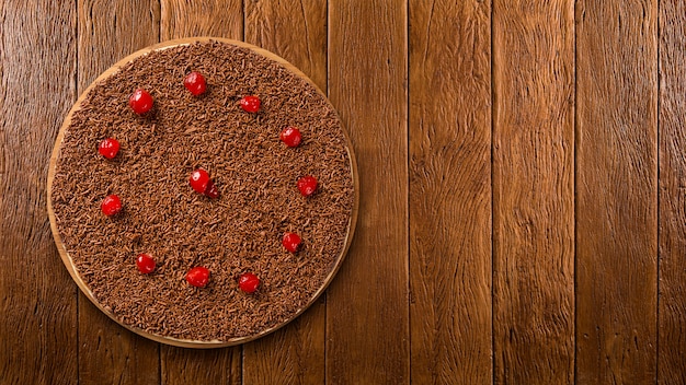 Süße rohe Pizza mit Schokolade und Kirsche auf hölzernem Hintergrund