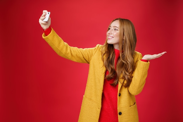 Süße rothaarige Frau, die im Park spazieren geht, entscheidet sich für ein Selfie in der Nähe einer wunderschönen Landschaft oder einer süßen Tiererweiterung ...