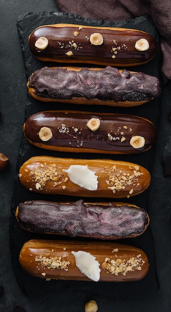 Süße Schokoladen-Eclairs auf schwarzem Holzbrett