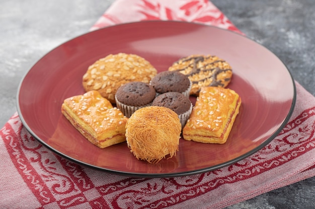 Süße Snacks in roter Platte auf einem Steintisch.