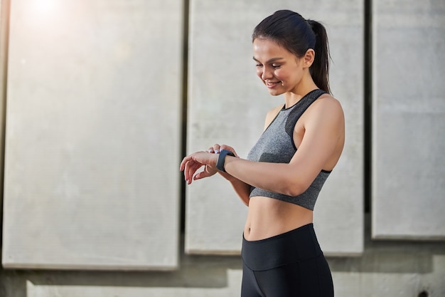 Foto süße sportlerin, die in halbposition steht und die nachricht auf ihren smartwatches liest, bevor sie läuft