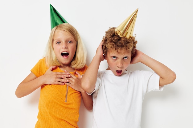 Süße stilvolle Kinder in bunten Mützen Geburtstagsurlaub Emotion isolierter Hintergrund unverändert