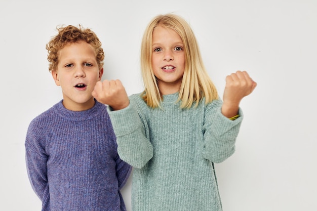 Süße, stylische Kinder in bunten Pullovern, die für einen unveränderten, lustigen Lebensstil posieren