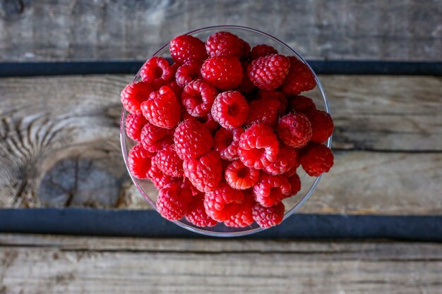 süße und gesunde Himbeeren in einer Glasplatte auf einem Holztisch